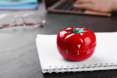 Timer em formato de tomate em cima de um caderno