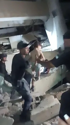 Rescatistas se pasan a un niño pequeño tras ser rescatado de entre los escombros de un edificio, después de que terremotos azotaran el país, en La Guaira.