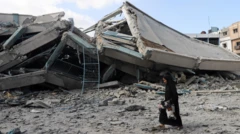 Uma mulher palestina carrega pertences enquanto caminha em meio aos escombros de uma escola das Nações Unidas, atingida por ataques israelenses no bairro de Zeitoun, na Cidade de Gaza, em 1º de outubro