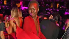 A modelo sul-sudanesa Alex Wek, de vestido vermelho em uma festa