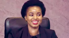 Foto of Senamile Masango dey wear all black suit and dey smile.