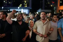 CHP İstanbul İl Başkanlığı önünde toplanan insanlar karanlıkta kol kola girmiş ve bir kişinin yumruğu havada