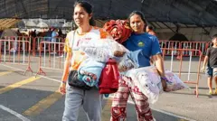 एक अस्थायी कैंप में शरण लेने जातीं दो महिलाएं