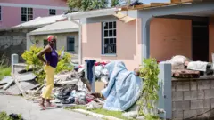 Mulher em frente à sua casa destruída em 22 de setembro de 2017 em Canefield, na ilha caribenha de Dominica, quatro dias após a passagem do furacão Maria