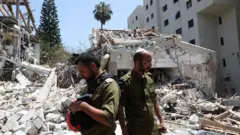 Membros das forças israelenses trabalham em um local atingido após um ataque de mísseis do Irã em Tel Aviv