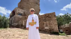 حارث الشريقي يقف أمام دار الحجر، صنعاء، اليمن