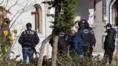 چند سرباز پولیس ترکیه با لباس‌های سیاه در مقابل یک منزل ایستاده اند.