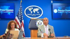 Barrack ve basın toplantısının moderatörünün göründüğü bir fotoğraf.