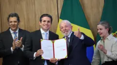 Lula posa com o presidente da Câmara, Hugo Motta, segurando o projeto de lei com sua proposta de reforma do IR