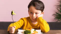 Хлопчик перед тарілкою з овочами