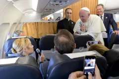 El Papa Francisco responde a una periodista en un avión durante uno de sus viajes.