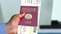 የኢትዮጵያን ፓስፖርት የያዘ የሰው እጅ
