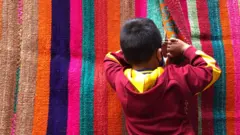 Un niño espía por el agujero de una manta.