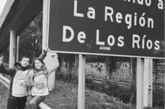 Marcos Reyes e Camila Gómez posando para foto ao lado de uma placa na estrada