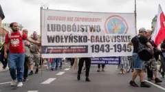 Протестувальники несуть банер з написом "Волинсько-галицький геноцид 1943-45 років" із зображенням перекресленого українського тризуба під час демонстрації у Варшаві, Польща, 12 липня 2026 року