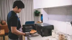 전자레인지에서 피자 한 조각을 꺼내는 남성의 모습