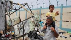 Un hombre con un niño a los hombros entre escombros en Rafah