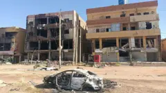 Ifoto igaragaza inyubako zangiritse n'imodoka yangiritse i Khartoum
