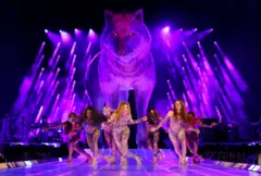 Shakira e suas bailarinas dançando. Atrás delas há uma estátua de uma loba