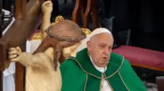 Çarmıha gerilmiş İsa heykeli yanında yeşil kostümüyle koltukta oturan Papa Françesko