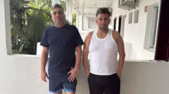 Carlos Alberto Rodelo y Jorge Cubillos en un hotel de Kinshasa, vestidos con franelas y shorts. 