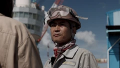 작업복을 입은 남성이 인터뷰어를 바라보고 있다 