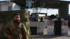 یک نیروی شورشی مخالف دولت پیشین سوریه از دروازه اصلی پایگاه نظامی روسیه در فرودگاه حمیمیم در نزدیکی شهر لاذقیه در غرب سوریه محافظت می‌کند