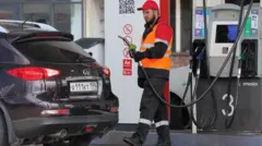 Сотрудник автозаправки у автомобиля