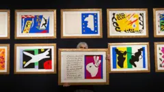 Una mujer sostiene una ilustración cerca de una colección de grabados originales de Henri Matisse de su portafolio de jazz en la casa de subastas Christie's el 17 de febrero de 2016 en Londres, Inglaterra