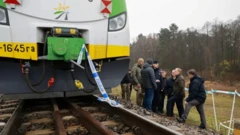 На путях стоит поезд, к нему привязана полицейская лента, у насыпи стоят люди.