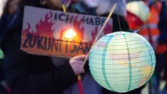 يتجمع مائة ناشط أمام كاتدرائية دوم ويحملون الفوانيس للاحتجاج على سياسة المناخ الألمانية التي لا تعالج أزمة المناخ في كولونيا، ألمانيا، في 14 نوفمبر/تشرين الثاني 2025، وسط قمة المناخ COP30 في البرازيل