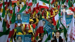 Manifestantes com bandeiras do Irã e fotografias de Massoud e Maryam Rajavi