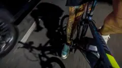 Close em uma perna pedalando uma bicileta ao lado de um carro