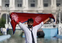 सिंहदरबारअगाडि नेपालको झण्डा देखाउँदै एक जेन जी प्रदर्शनकारी 