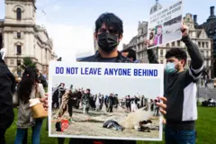 Wani mai zanga-zanga riƙe da kwali da ke "kada ku bar kowa a baya" lokacin zanga-zanga a birnin Landan.