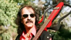 تصویر پرتره کوروش یغمایی، آهنگساز و خواننده راک ایرانی که یک گیتار بر دوش دارد