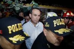 El presidente de Perú, José Jerí, tras dos policías, en una imagen nocturna.