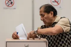 Un hombre deposita un papel en una urna de cartón.