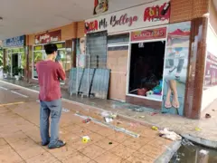 Una persona con un celular toma la foto de una tienda afectada