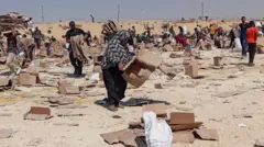 Palestinos se reúnem para recolher o que restou dos suprimentos de ajuda do centro de distribuição da Fundação Humanitária de Gaza, apoiada pelos EUA, em Rafah, no sul da Faixa de Gaza. Caixas de papelão vazias cobrem o solo árido