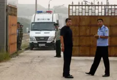 Agentes da policía chinesa esperam fora da prisão.