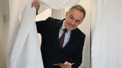 Социалист Эмманюэль Грегуар выходит из кабинки для голосования