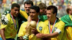 Romário segura o troféu da Copa do Mundo da Fifa ao lado de outros jogadores brasileiros durante a conquista do tetra, em 1994