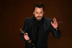 Kieran Culkin discursando, com estatueta na mão
