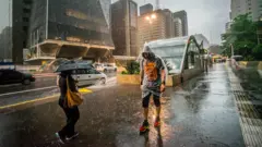 Pessoas andam na chuva91 betsSão Paulo