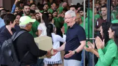 Тим Кук радостно улыбается, когда индийский мужчина стоит перед ним со старой моделью компьютера Apple на открытии первого магазина компании в Индии.