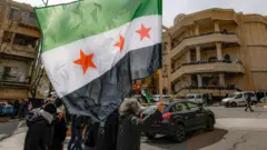 سكان في قرية مجدل شمس في هضبة الجولان المحتلة يلوحون بالعلم السوري الجديد