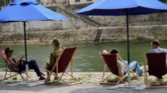 Varias personas descansando en la rivera del río Sena