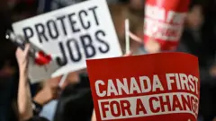 Comício, durante a eleição no Canadá, exibe cartazes como "Canada First" e "Protect Jobs"