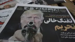 Экземпляры иранской ежедневной газеты «Хамшахри» с фотографией президента США Дональда Трампа и заголовком на персидском языке «Пустой пистолет санкций», в котором сообщается о новой жесткой экономической угрозе со стороны Трампа в адрес Ирана, у газетного киоска в Тегеране, Иран, 22 августа 2026 года.